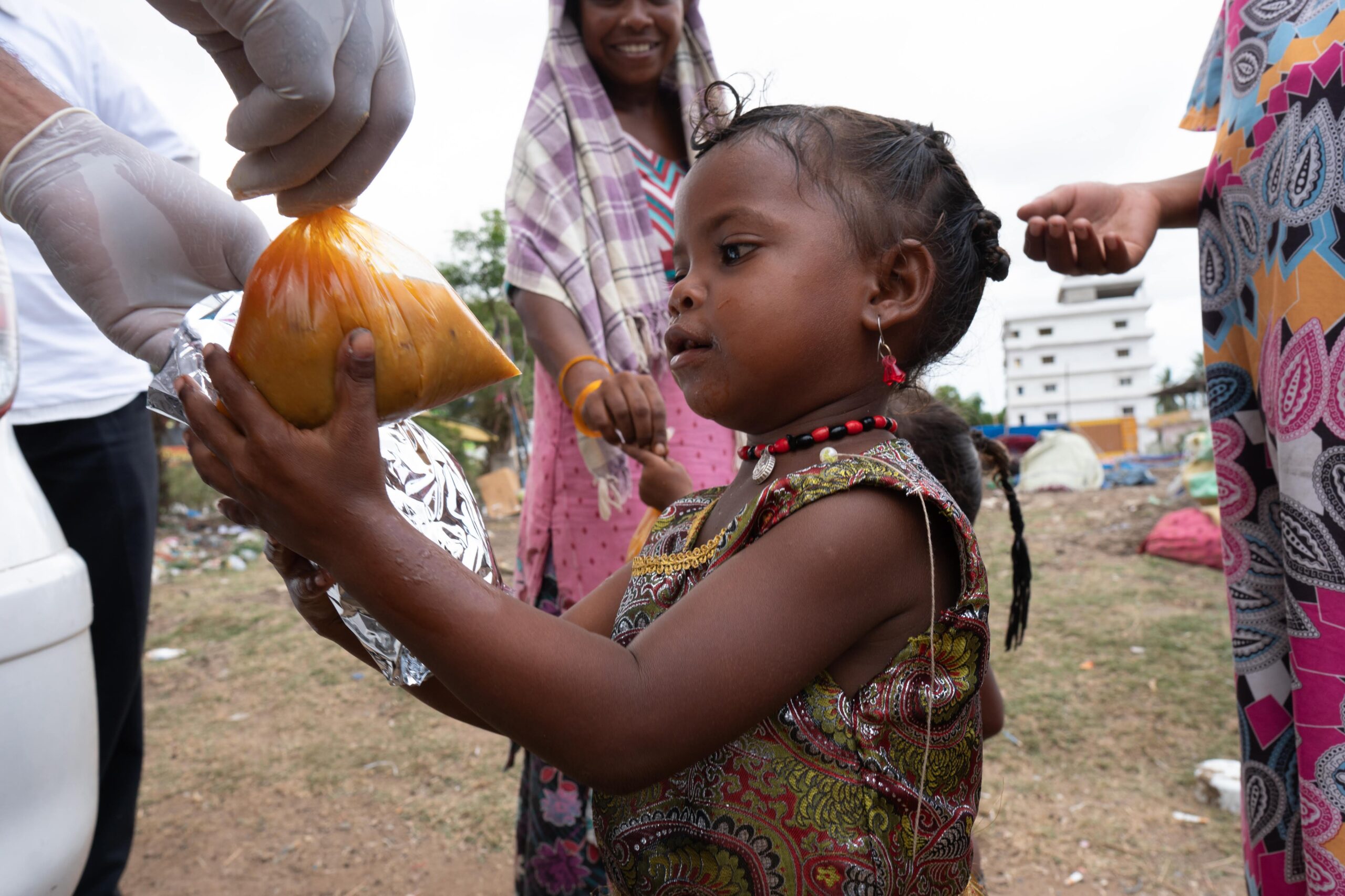 Young tribal girl holding a food bag being distributed during a community aid program in India